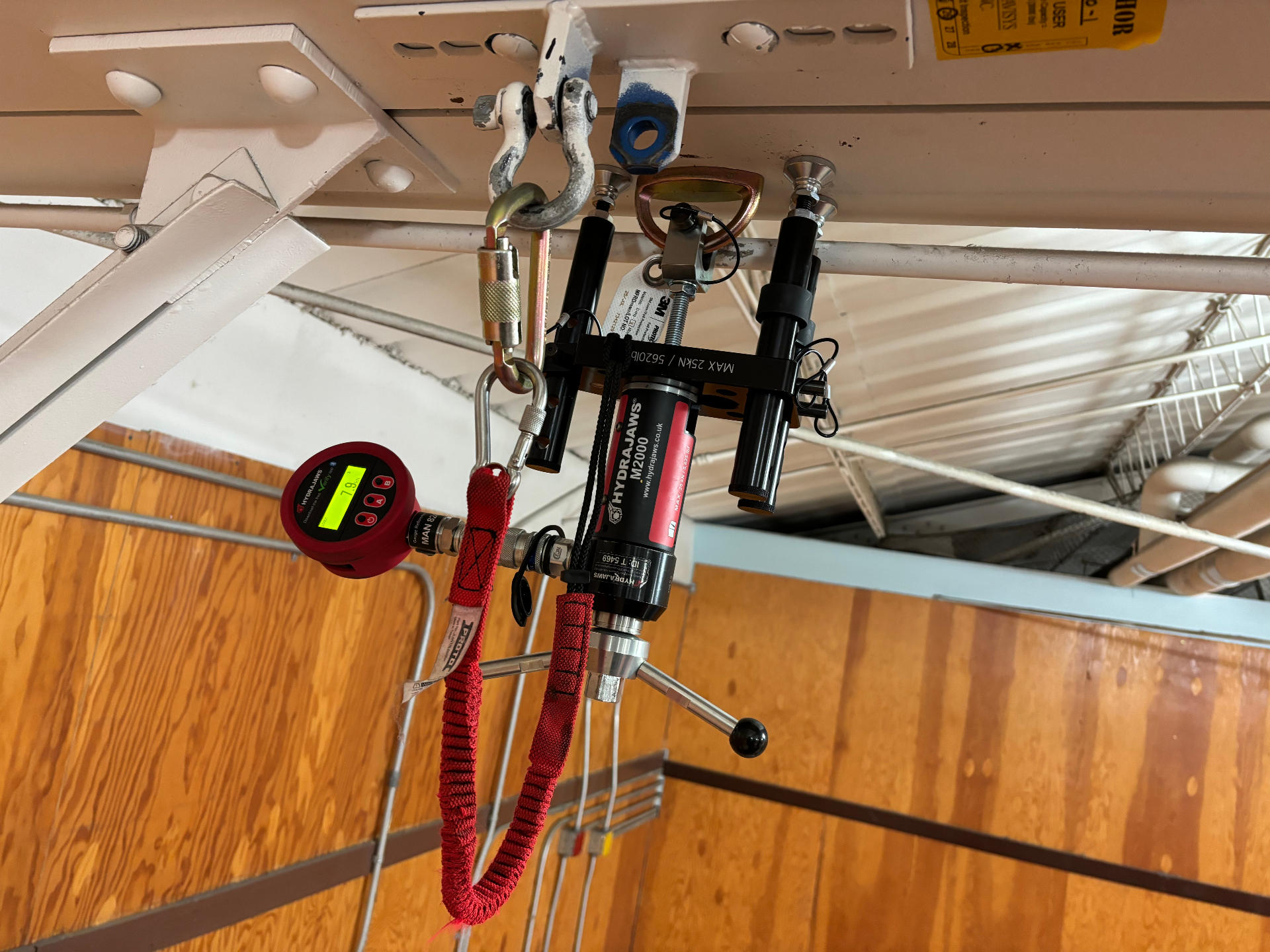 Close-up of an overhead single-point anchor connection and proof-loading setup during anchor pull testing