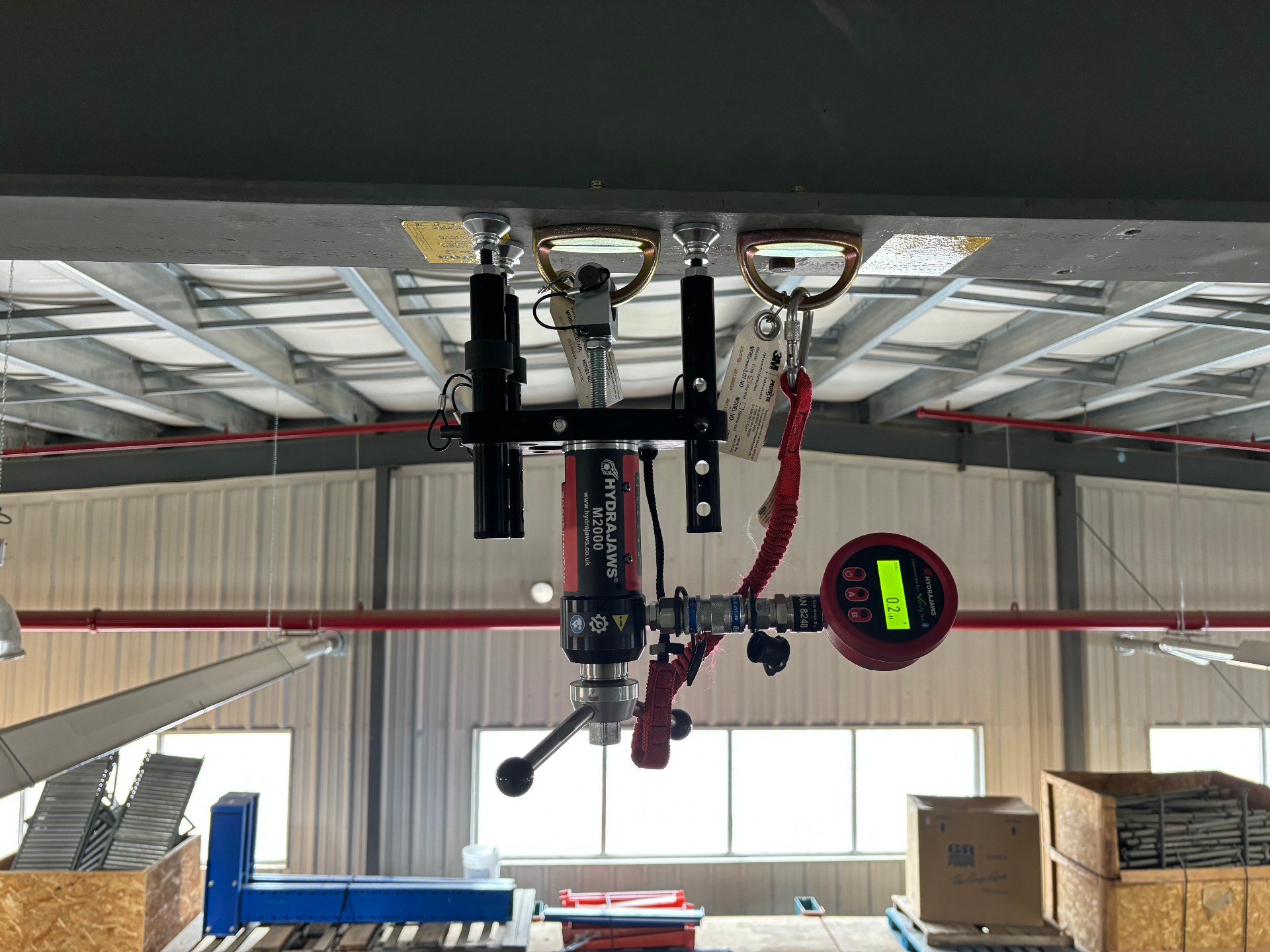 Overhead single-point anchor being pull tested from below using a Hydrajaws proof-loading rig and digital gauge