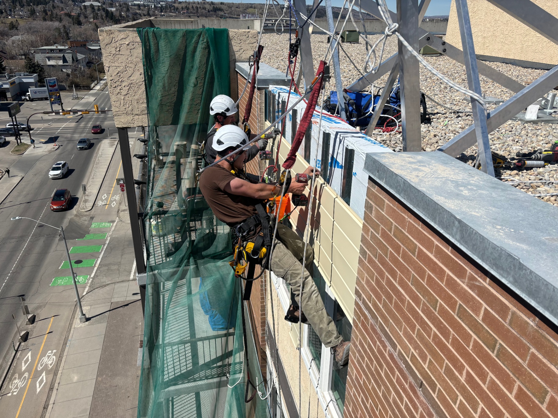 Cladding panel installation by rope access crew working from non-penetrating roof anchors