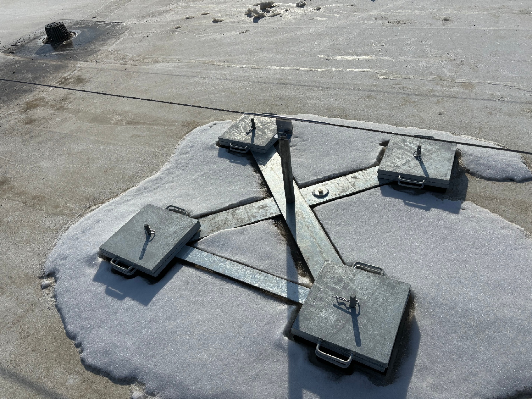 Close view of a counterweighted non-penetrating horizontal lifeline anchor base on a flat roof