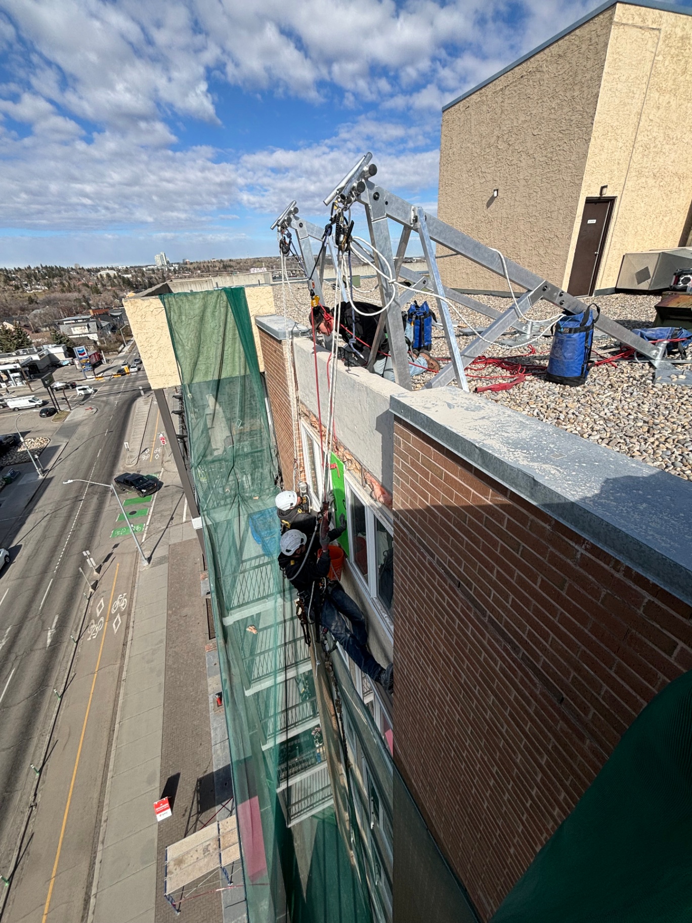 Window and facade repair from rope access, suspended from a non-penetrating ballasted roof anchor