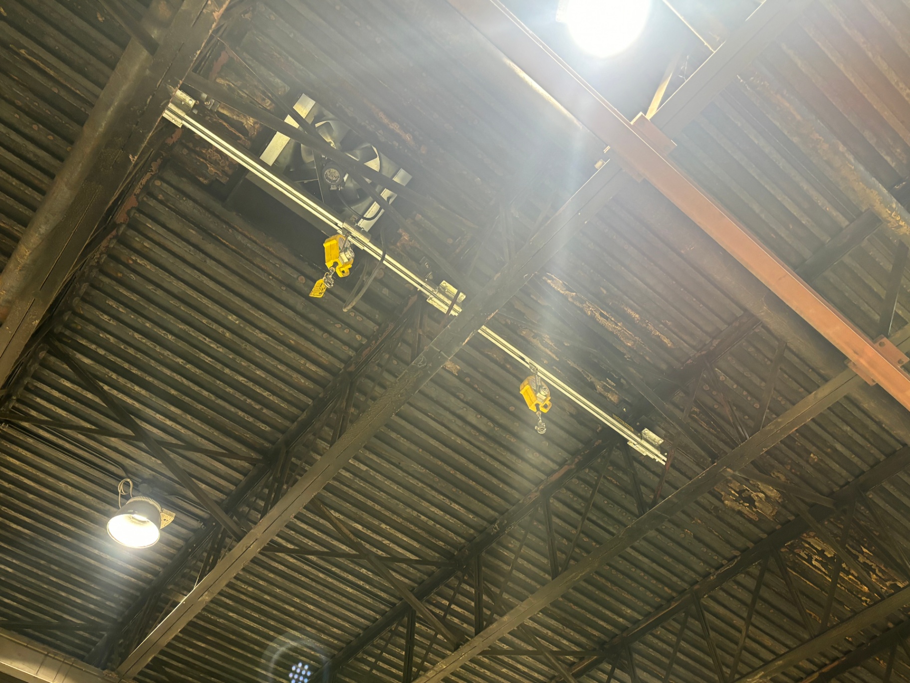 Parallel overhead rigid track runs covering adjacent warehouse bays for two-worker fall arrest coverage