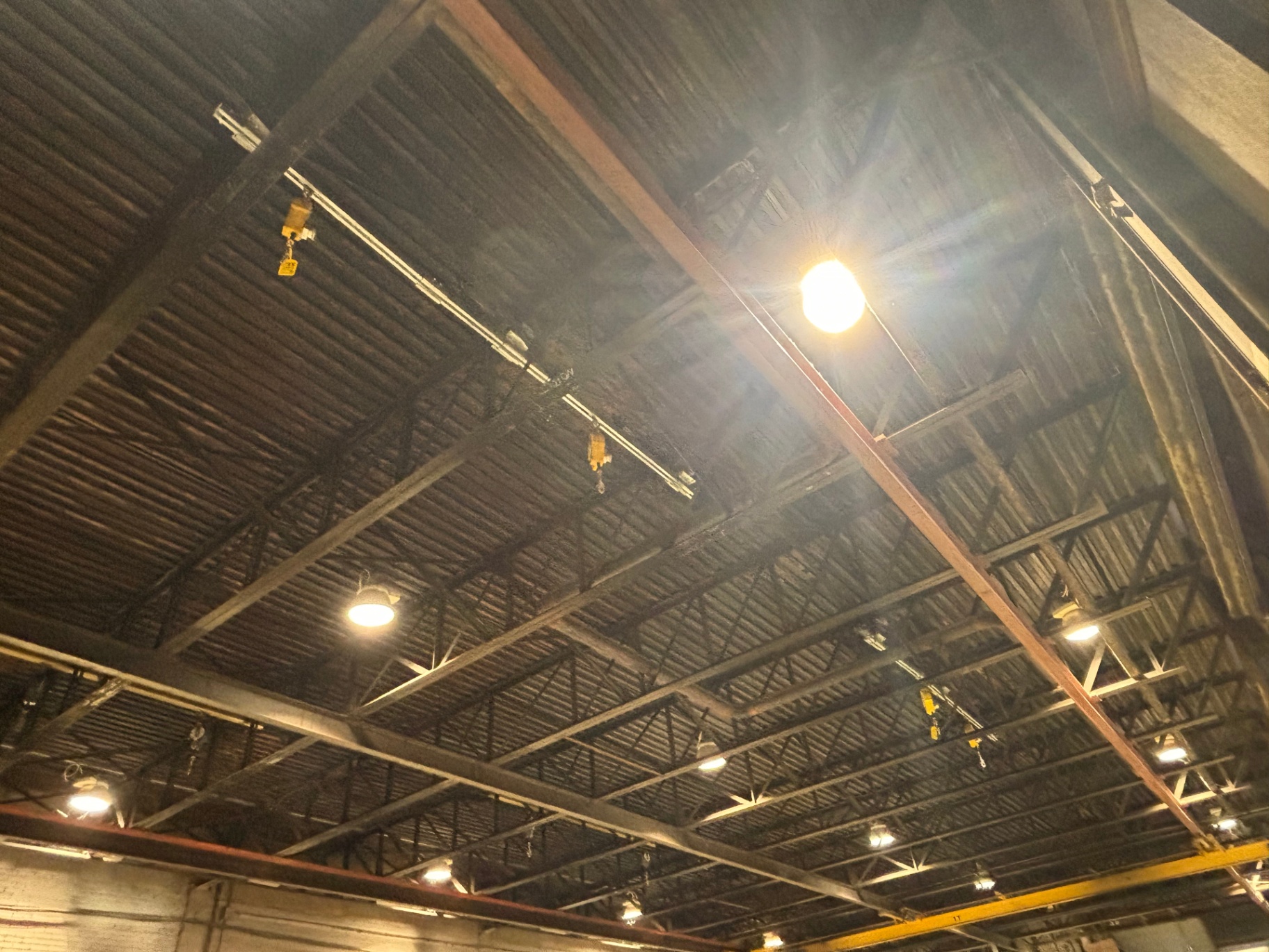 Overhead track fall arrest system installed across a full warehouse bay between steel trusses